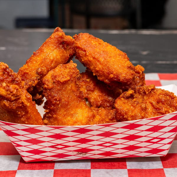 Crispy, golden-brown halal chicken wings in a red and white checkered paper tray.