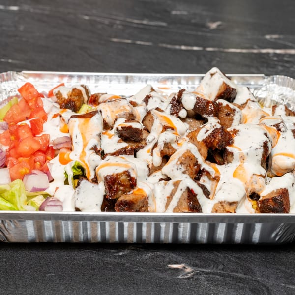 Halal Krush's halal meat and salad, topped with white and orange sauces, in a foil container.